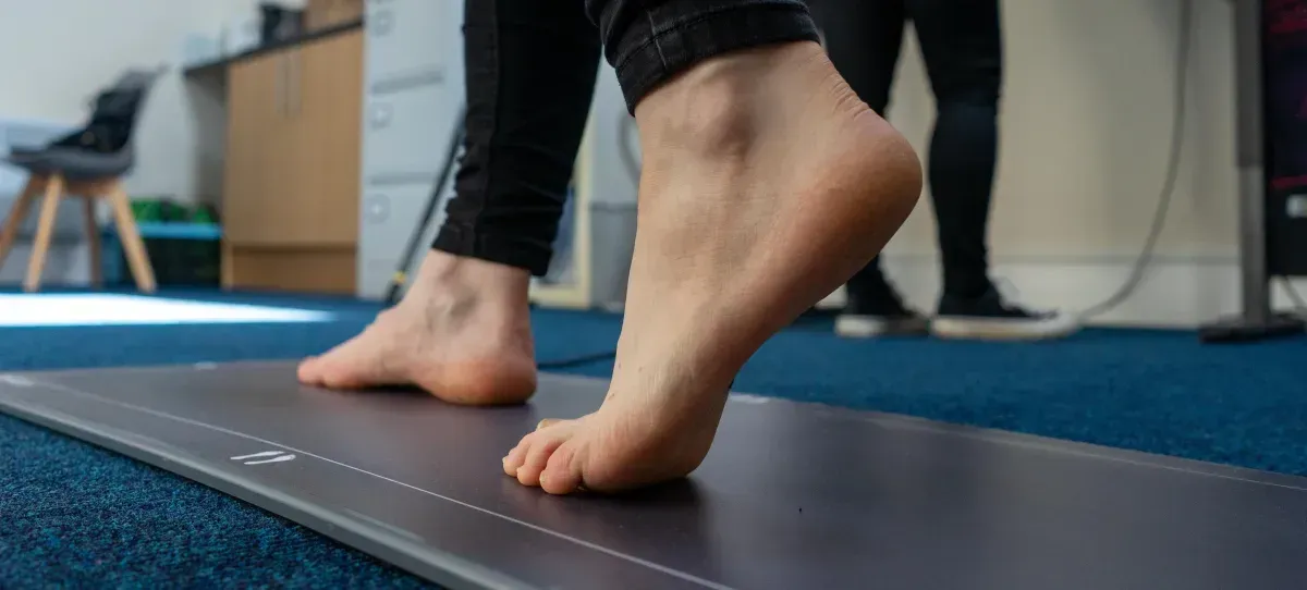 Patient walking barefoot over the Gaitscan plate for a foot strike analysis