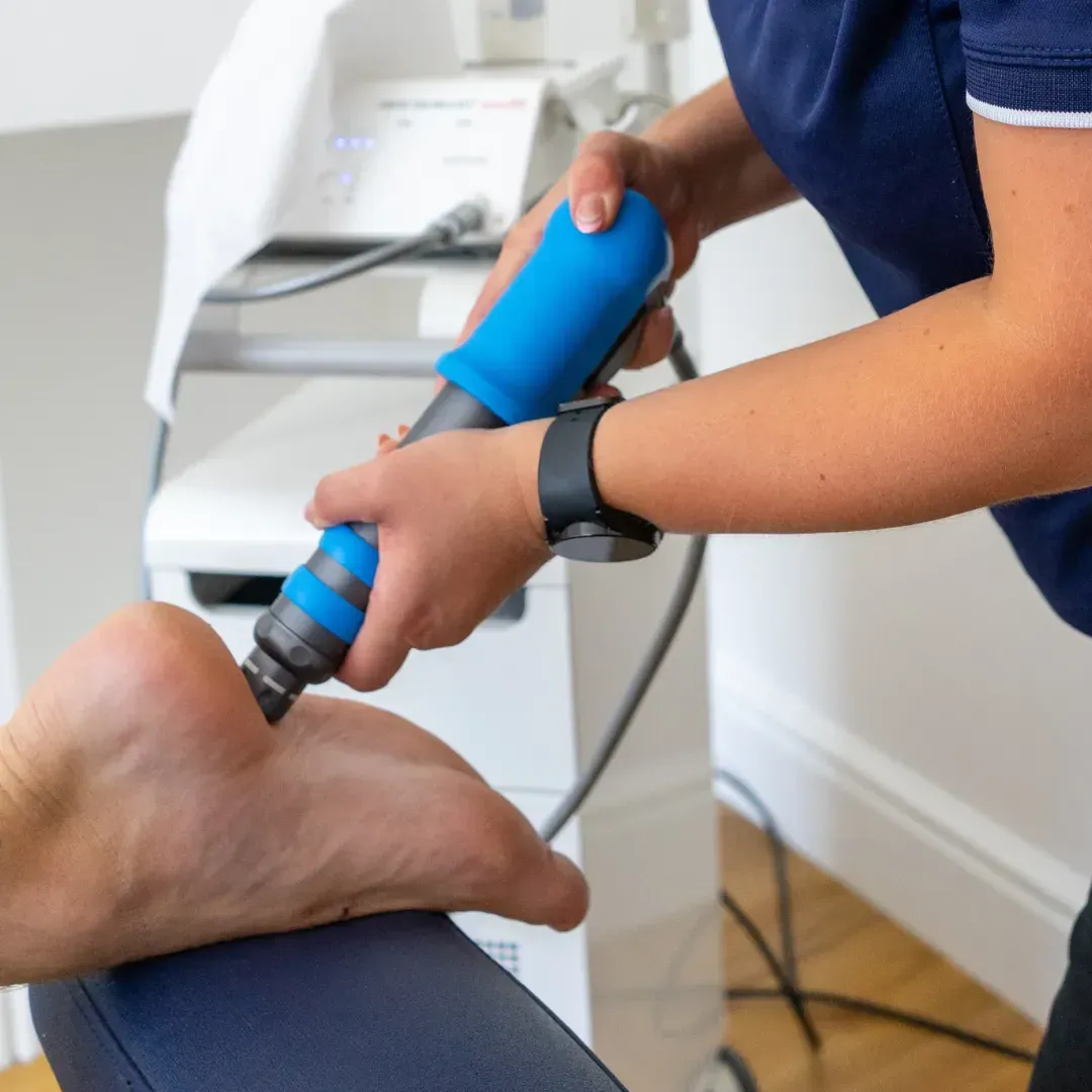 Shockwave therapy applicator held against the sole of a patient's foot
