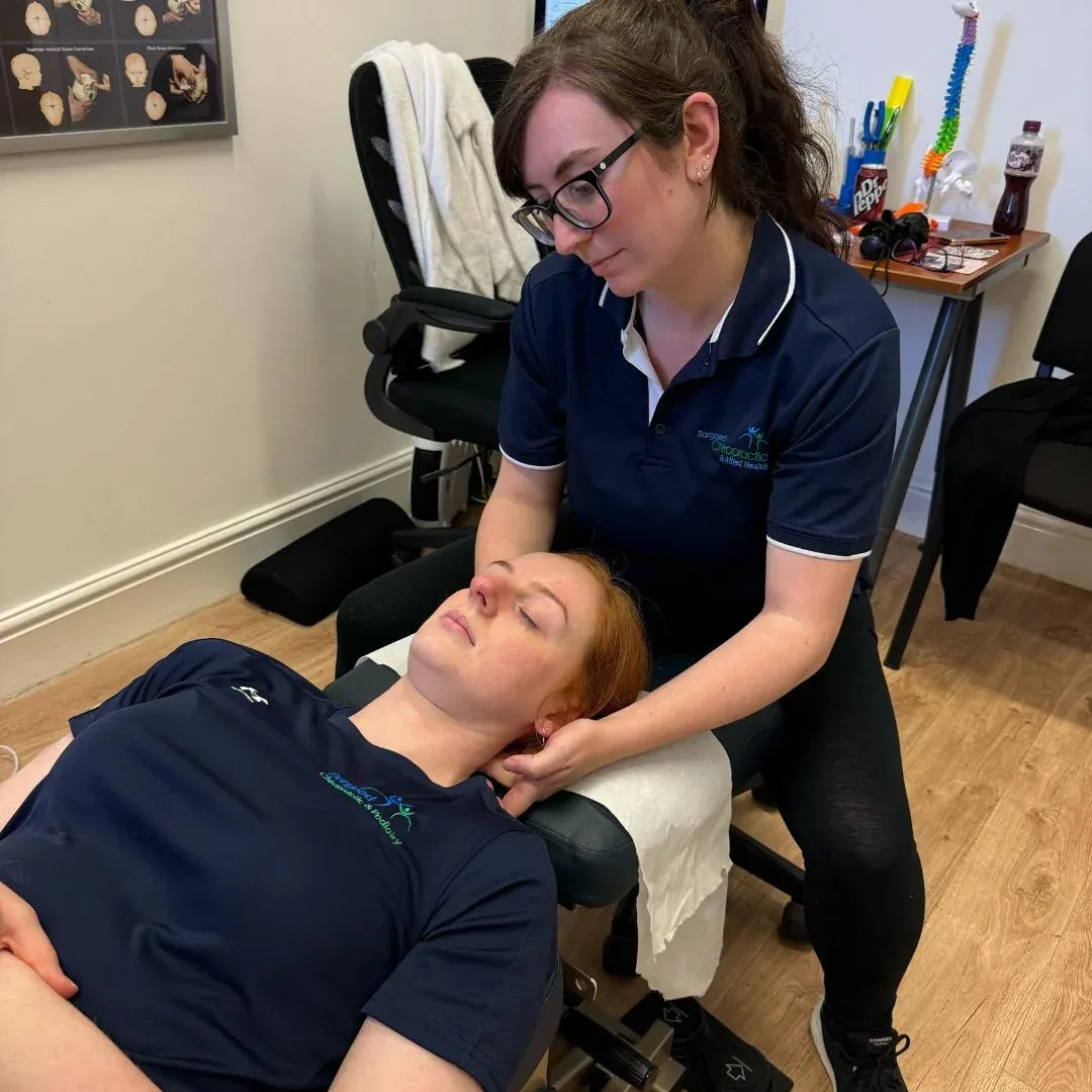 Practitioner supporting a patient's head during neck treatment on a couch